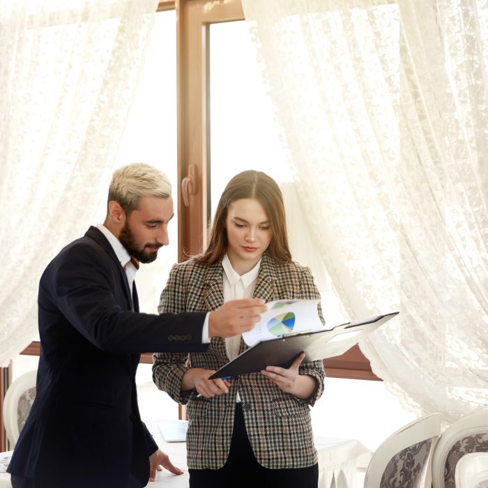 Handsome man and a brunette woman are looking at the diagramme, being in the light room